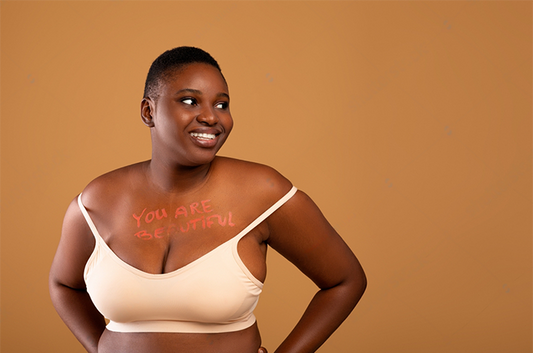 Free the buub - Body Neutrality, Self-Acceptance. You are beautiful motivational inscription written on chest of chubby black woman, plump young lady in bra posing over brown studio background, looking at free space